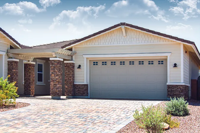 Tan short panel garage door with stockton windows installed on a residential home