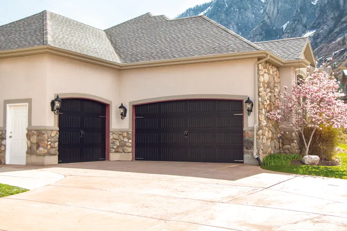 Black garage door with vertical short panels and decorative hardware